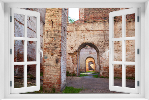 Fototapeta Naklejka Na Ścianę Okno 3D - The ruins of an old brick building, ruined walls, Old wall of a ruined red brick house with empty Windows and no roof.