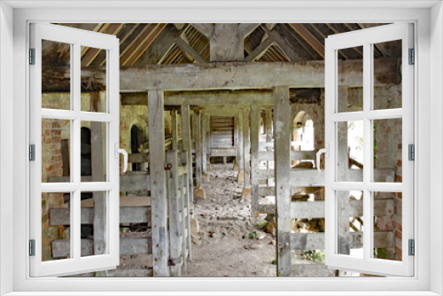 Fototapeta Naklejka Na Ścianę Okno 3D - The inside of an old stable. Timber beams divide the internal space.