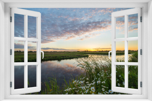 Fototapeta Naklejka Na Ścianę Okno 3D - Sunset with colorful clouds over the countryside near Gouda, Holland. Beautiful wild flowers grow along the waterfront in the foreground.