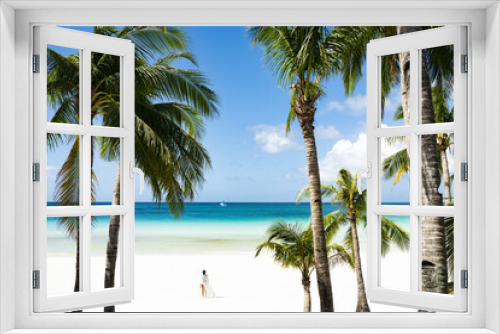 Fototapeta Naklejka Na Ścianę Okno 3D - (Selective focus) Stunning view of woman walking on a white sand beach bathed by a turquoise sea, beautiful coconut palm trees in the foreground. White Beach, Boracay Island, Philippines.
