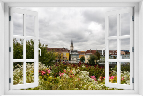 Fototapeta Naklejka Na Ścianę Okno 3D - The city of Villach, Austria is shown in background behind a row of colorful flowers. 