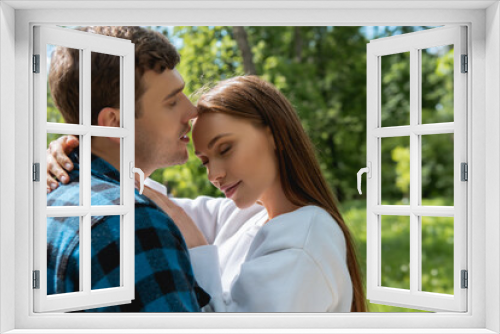 cheerful girl with closed eyes hugging handsome boyfriend