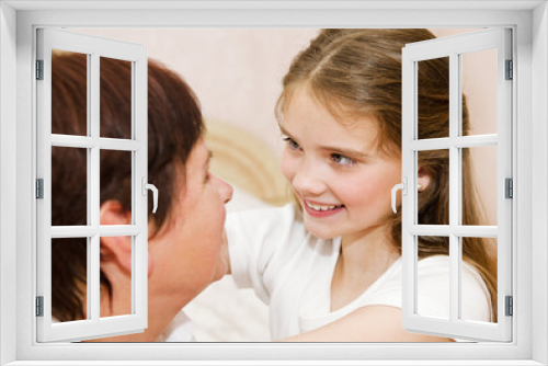 Cute little girl child and her grandmother are spending time together at home. Having fun, hugging and smiling