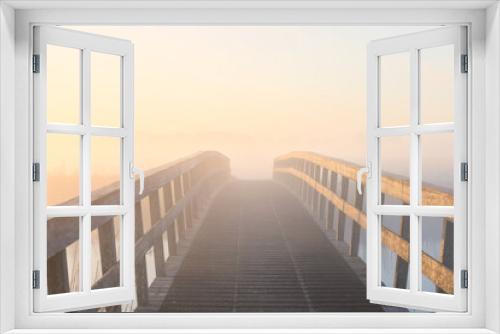 Fototapeta Naklejka Na Ścianę Okno 3D - wooden bridge in dense fog at sunrise