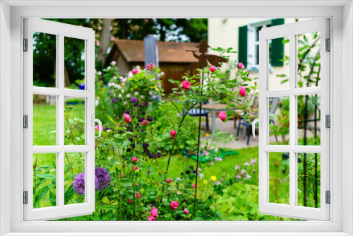 Fototapeta Naklejka Na Ścianę Okno 3D - Sommer im Garten mit Rosenbeeten und Staudenbeeten, blick in Garten mit Hochbeeten, Terrasse, Gartenmöbel und blühenden Rosen