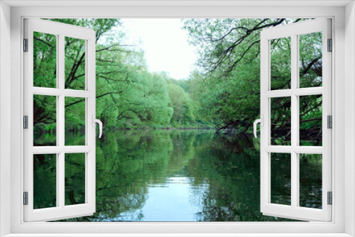 Fototapeta Naklejka Na Ścianę Okno 3D - Reflection of green trees and banks in a calm river in the summer. River rafting in summer. Packrafting in wilderness.