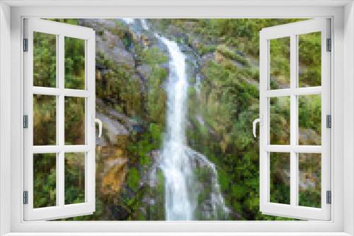 Fototapeta Naklejka Na Ścianę Okno 3D - A waterfall spotted in Tal, Annapurna Circuit Trek, Nepal. Few hundred meters of free fall, waterfall surrounded by tall mountains slopes, covered with green bushes and trees. Smooth capture