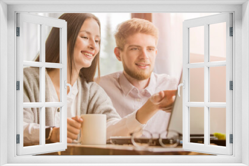 A man and a woman are working at a table at home. Married couple in the living room with laptops. A guy and a girl work from home during 
quarantine, family searching information in internet.