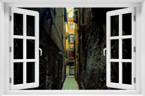 Fototapeta Naklejka Na Ścianę Okno 3D - A dark and gloomy narrow alleyway with old buildings on either side