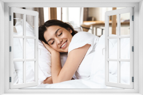 Photo of pretty brunette woman smiling while lying on bed