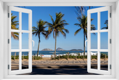 Fototapeta Naklejka Na Ścianę Okno 3D - Palm trees on the boulevard of Ipanema with Portuguese tile pavement in the foreground and beach, ocean and islands out off the coast  in the background