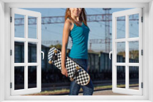 Portrait of attractive girl with a skateboard. Woman on railway station
