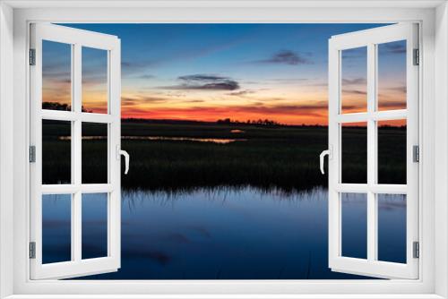 Fototapeta Naklejka Na Ścianę Okno 3D - orange sunset over blue swamp water