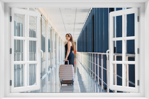 Young woman with luggage at the international airport. She is very happy of her vacation at warm country on christmas holidays