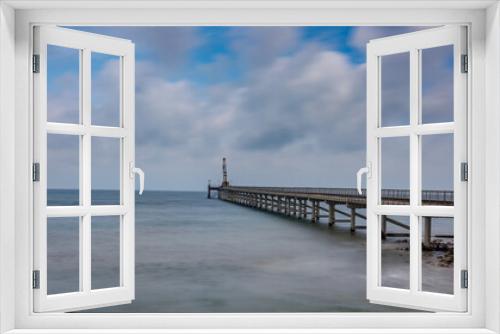 Fototapeta Naklejka Na Ścianę Okno 3D - A horizontal shot of a wooden deck on a beautiful sandy beach under puffy clouds