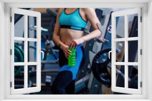 Young girl at the gym trainer holding a bottle of water. Fitness girl with perfect sculpted muscular and tight body. Sports motivation. Heathy lifestyle, sport conception