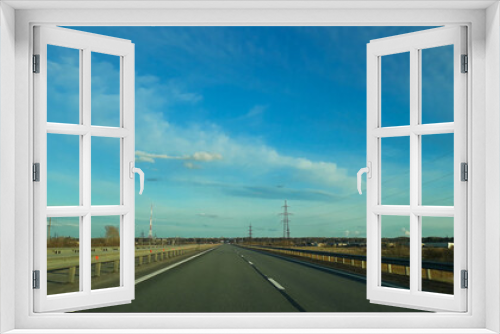 Fototapeta Naklejka Na Ścianę Okno 3D - A road or highway leading to the horizon. View from the car window. Northern dim summer, blue sky with white clouds. Journey, the way home.