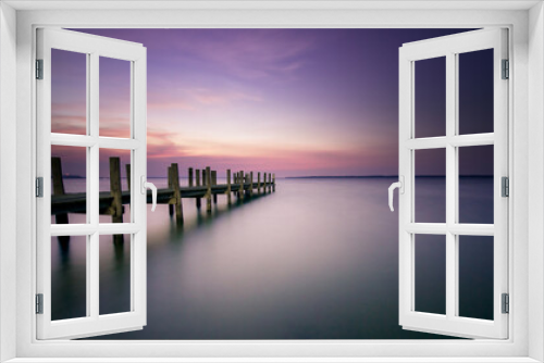 Fototapeta Naklejka Na Ścianę Okno 3D - Purple and pink sunset over smooth water and pier