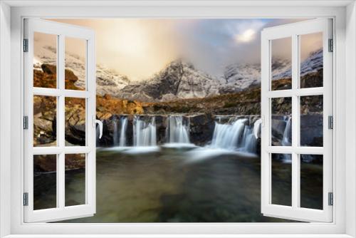 Fototapeta Naklejka Na Ścianę Okno 3D - Stunning cascade waterfall at the Fairy Pools on the Isle of Skye in the Scottish Highlands. Taken in the evening golden hour, beautiful light from the sun can be seen in the Winter landscape.