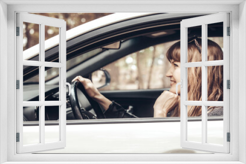 Smiling girl with her hair behind the wheel of a white car