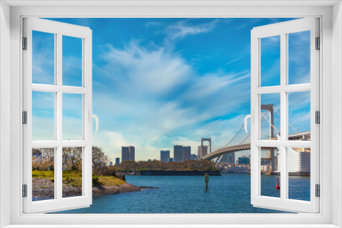 Fototapeta Naklejka Na Ścianę Okno 3D - Bird Island of Odaiba Bay in front of the double-layered suspension Rainbow Bridge in the port of Tokyo with cirrus clouds in the sky.