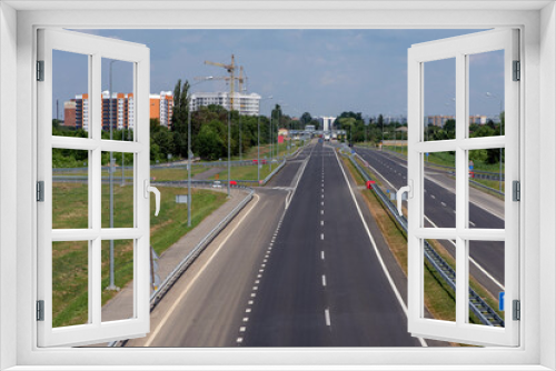 Fototapeta Naklejka Na Ścianę Okno 3D - Highway against the background of high-rise buildings and a construction crane at the entrance to the city.