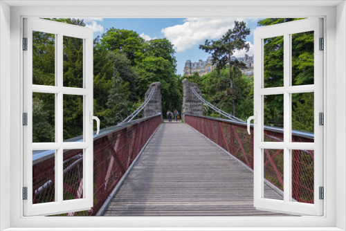 Fototapeta Naklejka Na Ścianę Okno 3D - 63-meter-long suspension bridge (1867) in Buttes-Chaumont Park (Parc des Buttes-Chaumont, 1867) - Public Park situated in northeastern Paris, fifth-largest park in Paris. Paris. France.