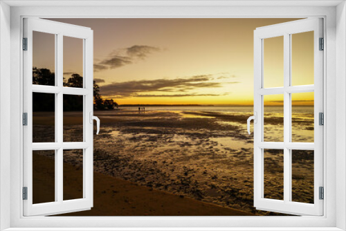 Fototapeta Naklejka Na Ścianę Okno 3D - Golden glow of sunset on the beach at low tide, with silhouette of two people in the distance. Dunwich, North Stradbroke Island, Queensland, Australia.