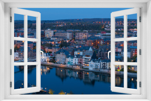 View of Namur and Jambes at sunset when the lights switch on and the reflection of the houses on the Meuse river.