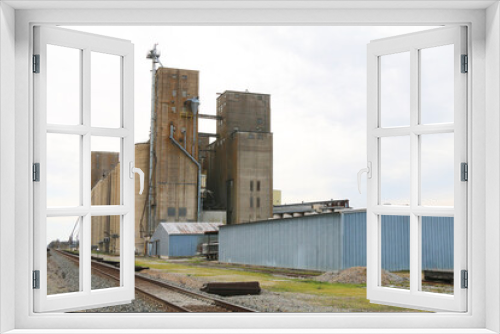Fototapeta Naklejka Na Ścianę Okno 3D - very large working agricultural farm community feed grain and corn silo building next to railroad track in rural heartland america perfect for farming and agriculture stock imagery