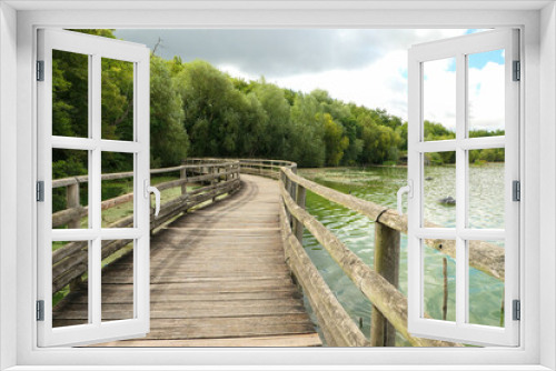 Fototapeta Naklejka Na Ścianę Okno 3D - Long wooden bridge above the water. Landscape by the lake with the forest in the background. Summer scene.