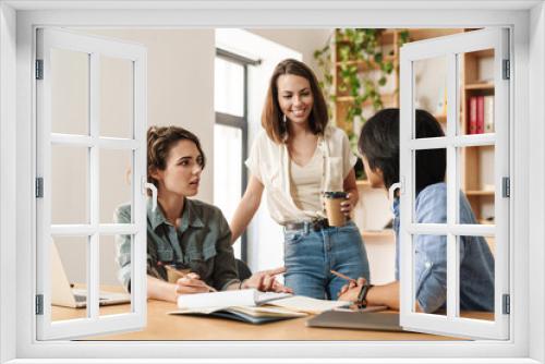 Image of colleagues discussing project while working with laptops