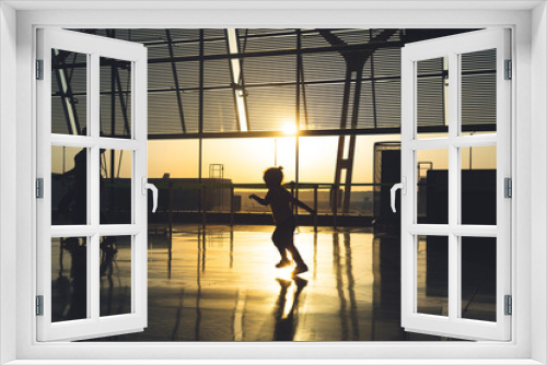 silhouette of an unrecognizable  child running through the airport terminal at sunrise.