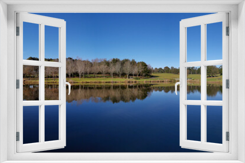 Fototapeta Naklejka Na Ścianę Okno 3D - Beautiful morning view of a peaceful pond in a park with reflections of deep blue sky and tall trees, Fagan park, Galston, Sydney, New South Wales, Australia