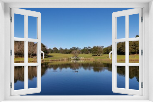 Fototapeta Naklejka Na Ścianę Okno 3D - Beautiful morning view of a peaceful pond in a park with reflections of deep blue sky and tall trees, Fagan park, Galston, Sydney, New South Wales, Australia
