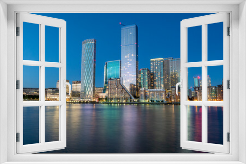 Fototapeta Naklejka Na Ścianę Okno 3D - Financial district of London city Canary Wharf reflected on the Thames river at blue hour in England