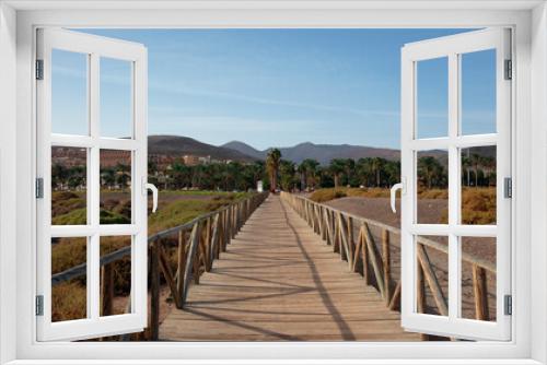 Fototapeta Naklejka Na Ścianę Okno 3D - Wooden boardwalk connecting Jandia salt marsh, an unusual protected natural habitat and Morro Jable lighthouse to the coquette resort in the south of the island of Fuerteventura, Canary Islands, Spain