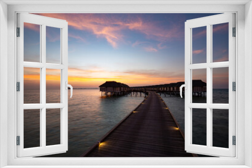 Fototapeta Naklejka Na Ścianę Okno 3D - Sunset on Maldives island, luxury water villas resort and wooden pier. Beautiful sunset sky and clouds and tropical beach background for summer vacation holiday and travel concept banner
