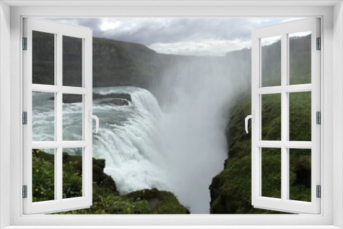 Fototapeta Naklejka Na Ścianę Okno 3D - Misty expansive waterfall in lush green mountain terrain