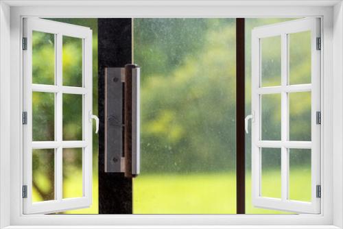 Fototapeta Naklejka Na Ścianę Okno 3D - Dusty window glass, slide door handle, against sunny day outdoor in background