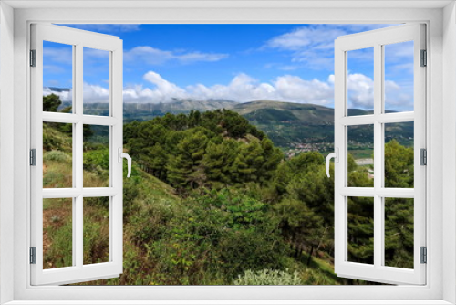 Fototapeta Naklejka Na Ścianę Okno 3D - Walking path in lovely green nature with clouds and mountains in the background during a sunny day, Berat