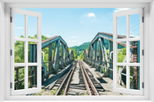 Fototapeta Naklejka Na Ścianę Okno 3D - Railway bridge over river in Polish mountain. Heavy rusty steel old industrial train overpass in natural scenic landscape, blue summer sky.
