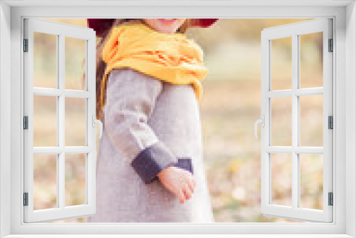 Fototapeta Naklejka Na Ścianę Okno 3D - Beautiful little girl in a gray coat, a yellow scarf and a burgundy hat posing for the camera in an autumn park