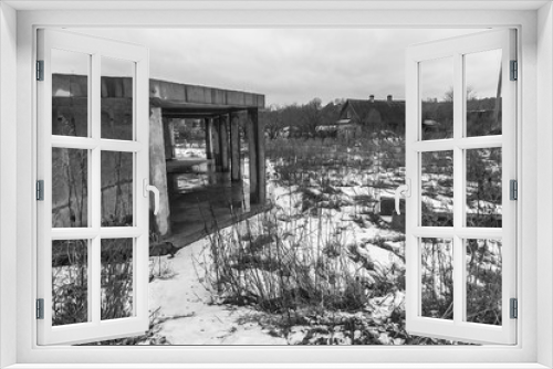 Fototapeta Naklejka Na Ścianę Okno 3D - Unfinished concrete house on the banks of a frozen river