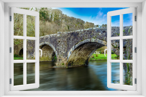 Fototapeta Naklejka Na Ścianę Okno 3D - A long exposure view to produce smooth, dreamy water flowing beneath the Llawhaden bridge, an eighteenth-century, grade 2 listed bridge that spans the River Cleddau, Wales