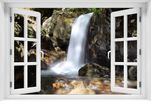 Fototapeta Naklejka Na Ścianę Okno 3D - Mountain waterfall flows among green forest and runs down the beautiful gray stones. Amazing summertime wallpaper background.