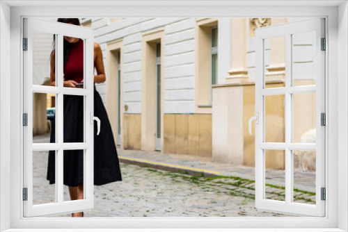 Image of a beautiful stylish woman on a summer day with walking on an empty street and holding a mobile phone in a city center scene