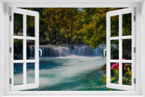 Fototapeta Naklejka Na Ścianę Okno 3D - View of flowing Manavgat Waterfall in Antalya, Turkey, with green trees around, on cloudy blue sky background. July 2020, long exposure picture