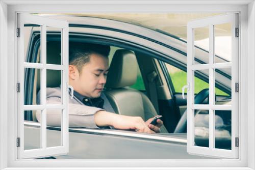 Happy businessman using smartphone calling while driving the car on his morning commute to work. Handsome Asian young man touching mobile phone communication on his luxury automobile on the road trip.