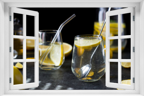 Fototapeta Naklejka Na Ścianę Okno 3D - Two glasses of lemonade on a black background. Lemon slices and mint leaves float in the water and lie next to each other on the table